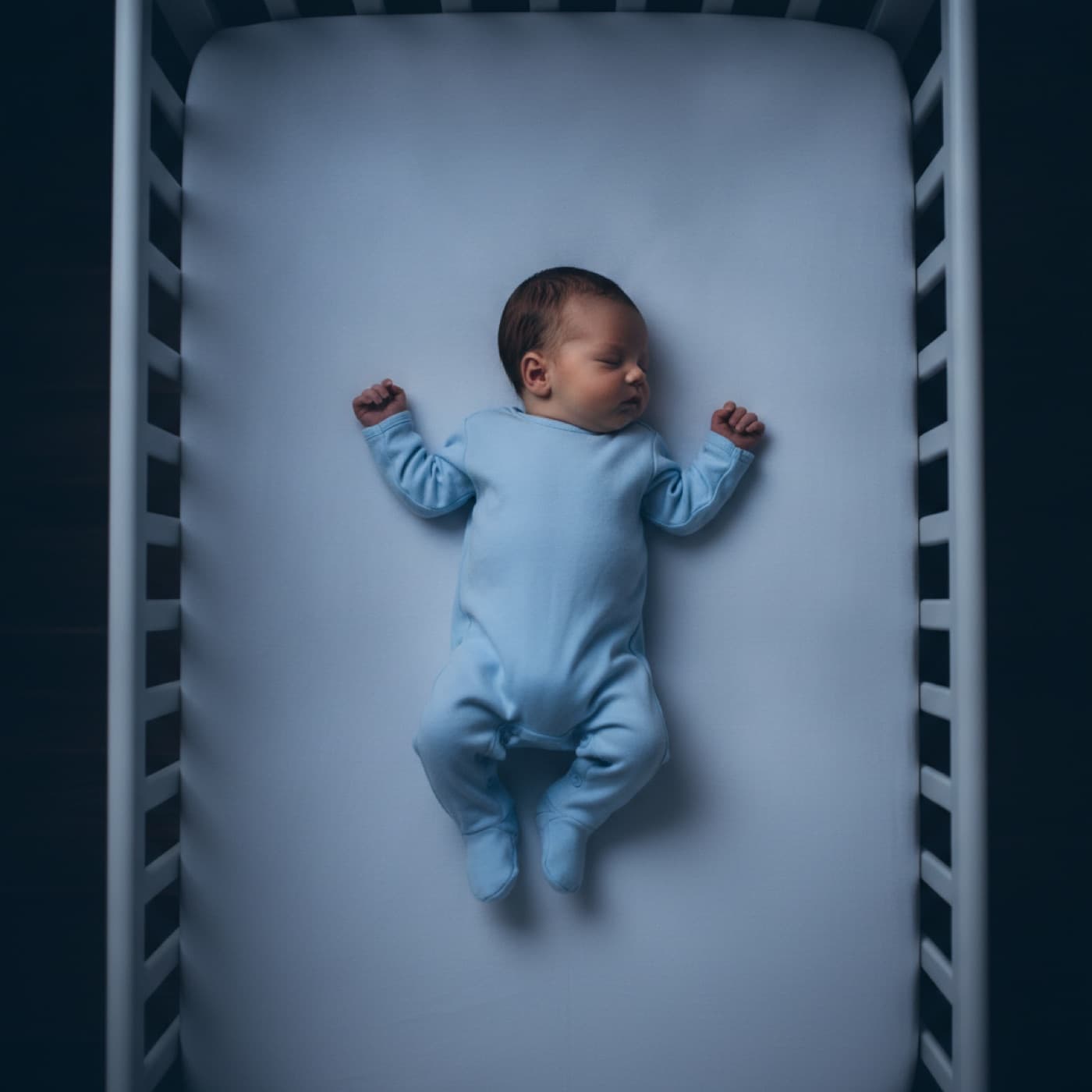 A baby sleeping safely on its back in a bare crib